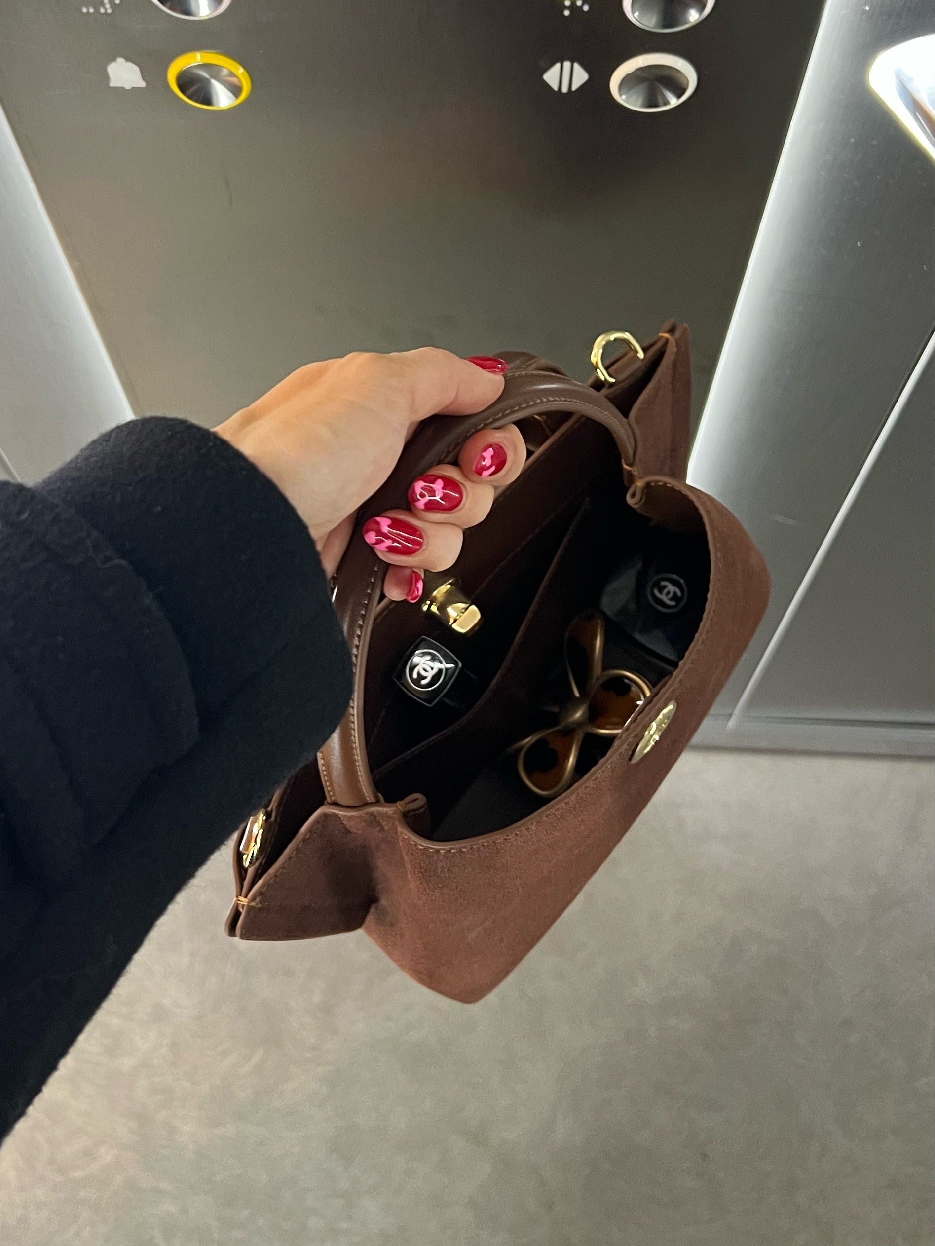 A hand holding a mini bag in an elevator.