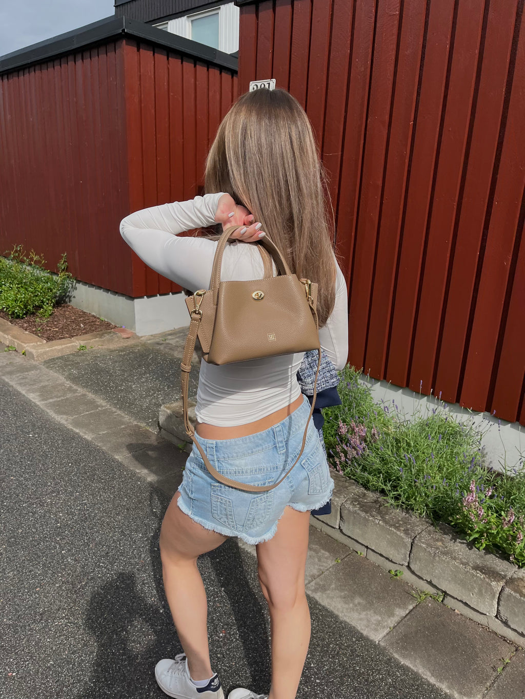A girl walking on a street holding a mini bag.
